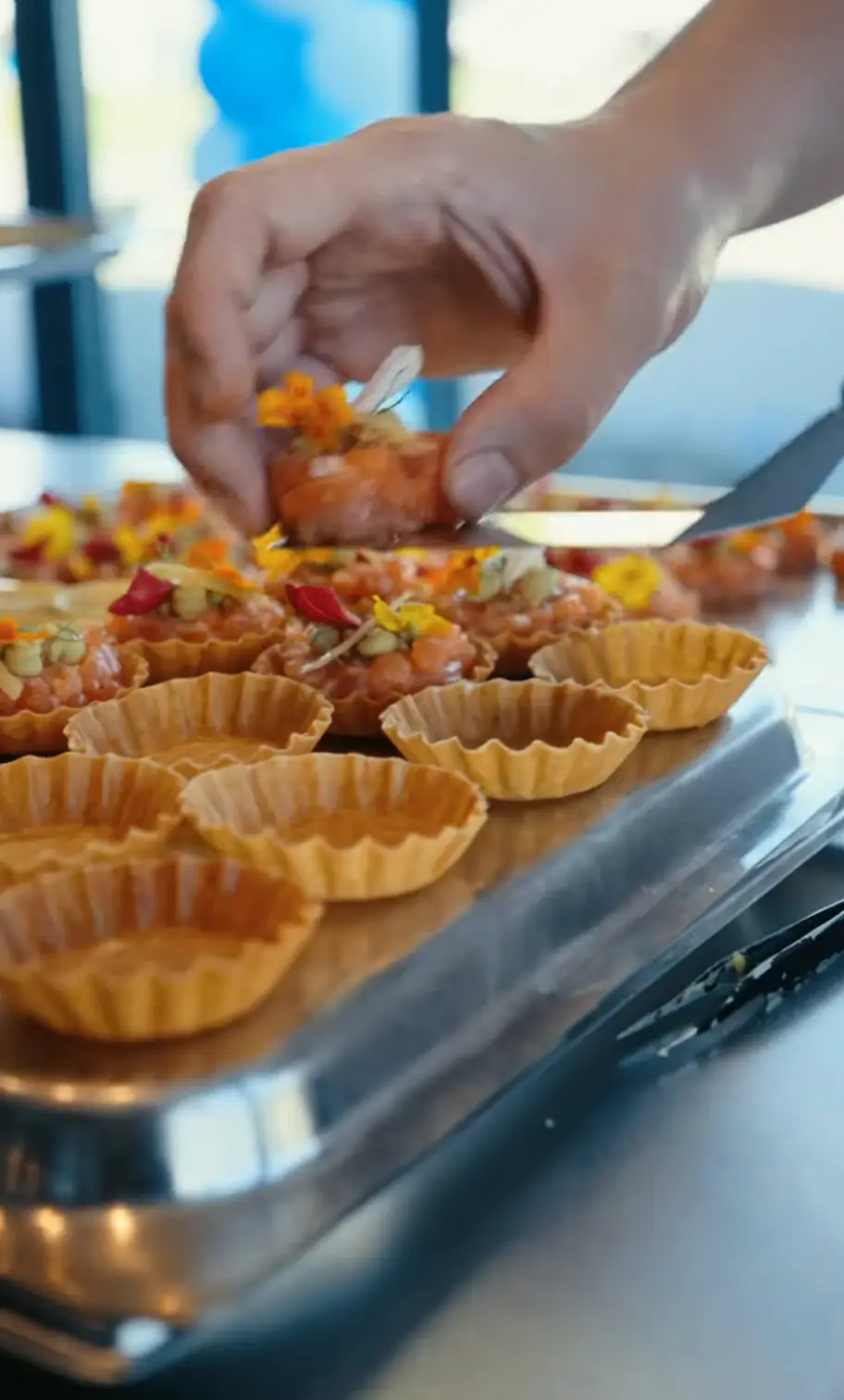 Chef dressant une assiette avec des fleurs comestibles en cuisine professionnelle